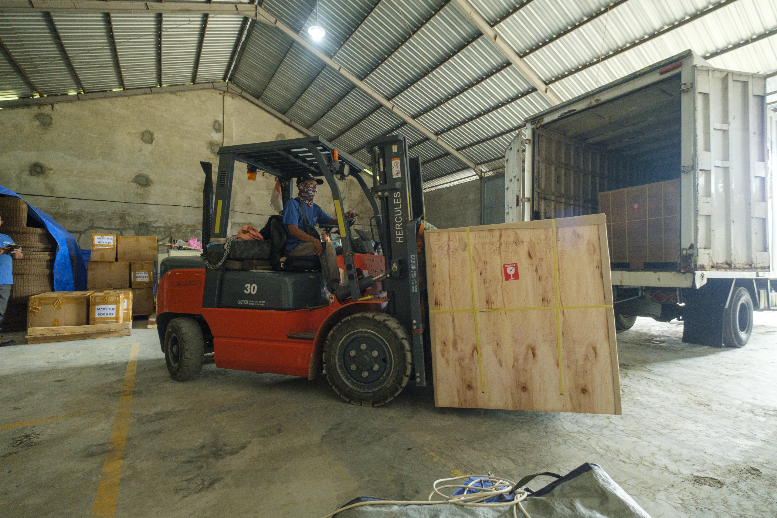 Forklift loading a wooden crate into a container in Bali